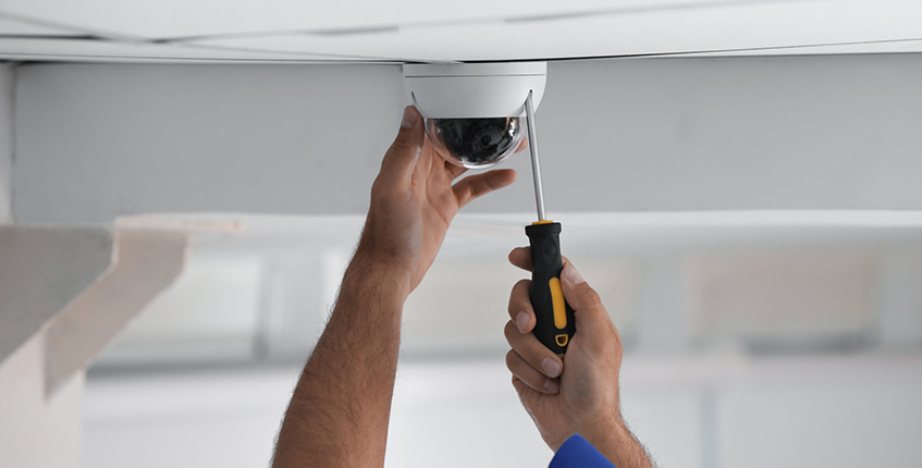 technician installing security camera on ceiling